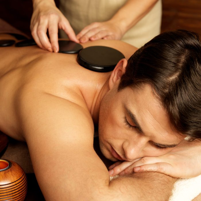 Handsome man having stone massage in spa salon. Healthy lifestyle.